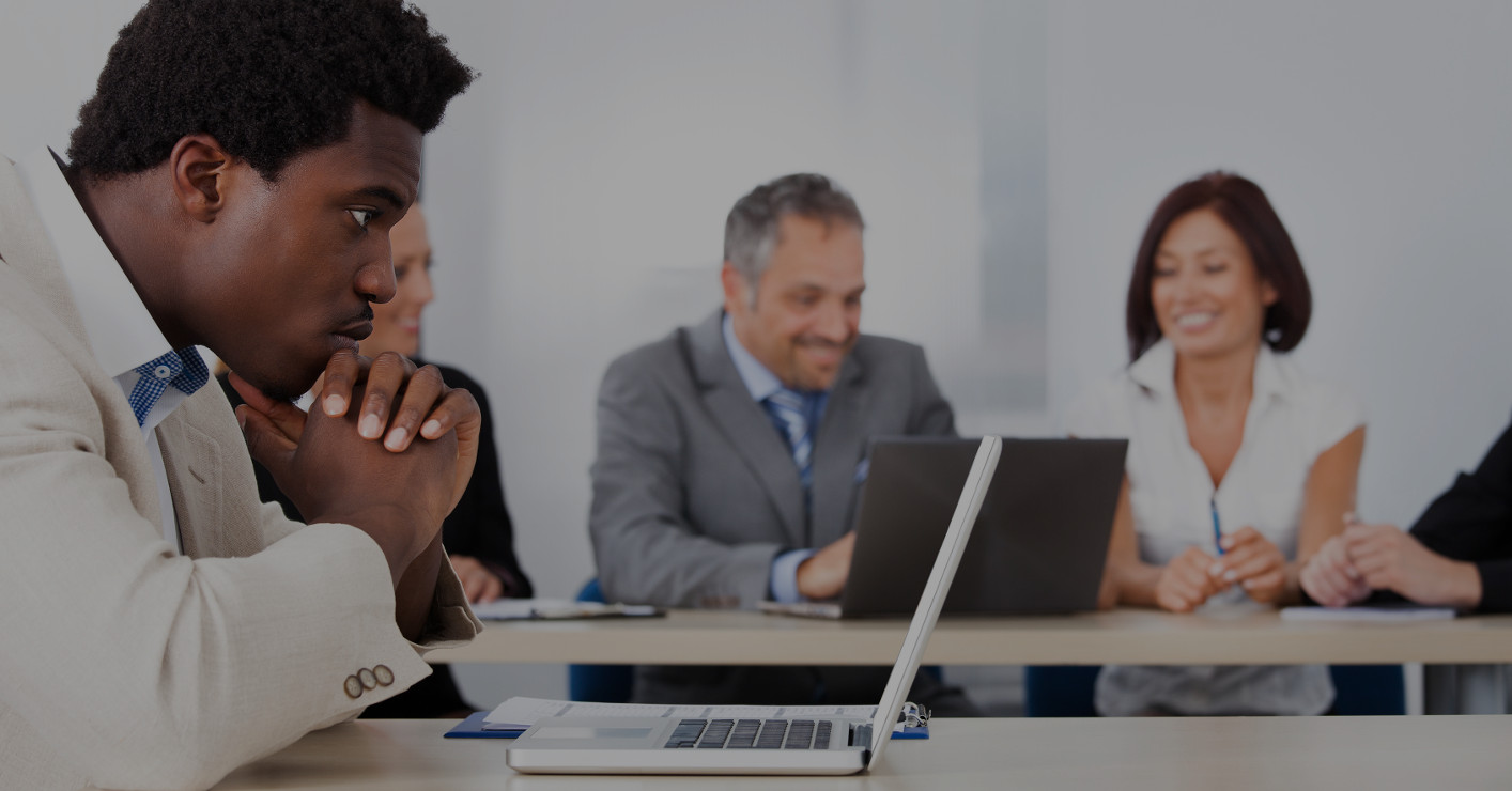 Contemplated African Businessman Looking At Laptop In Front Of Colleagues